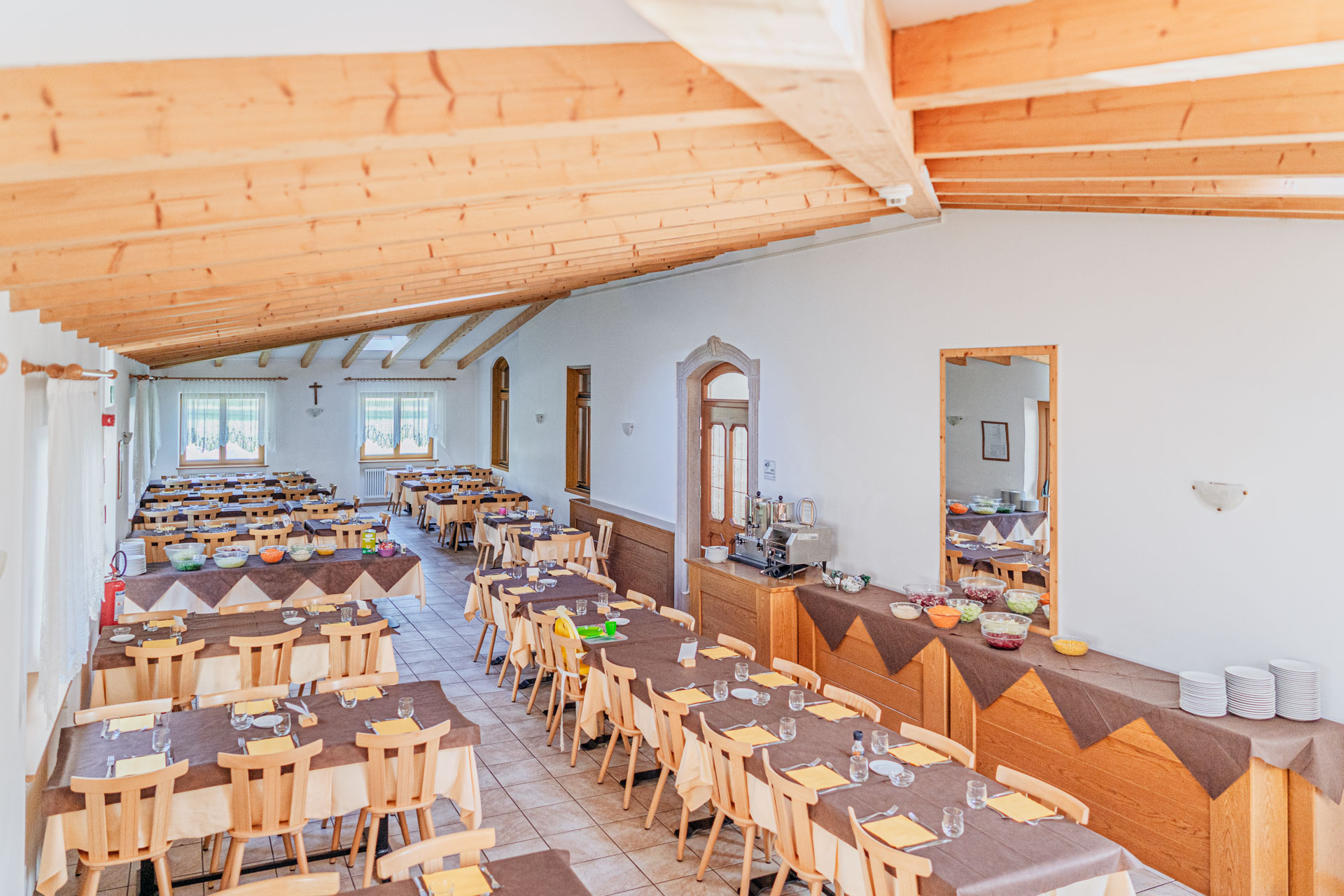 Sala ristorante con travi in legno e tavoli apparecchiati